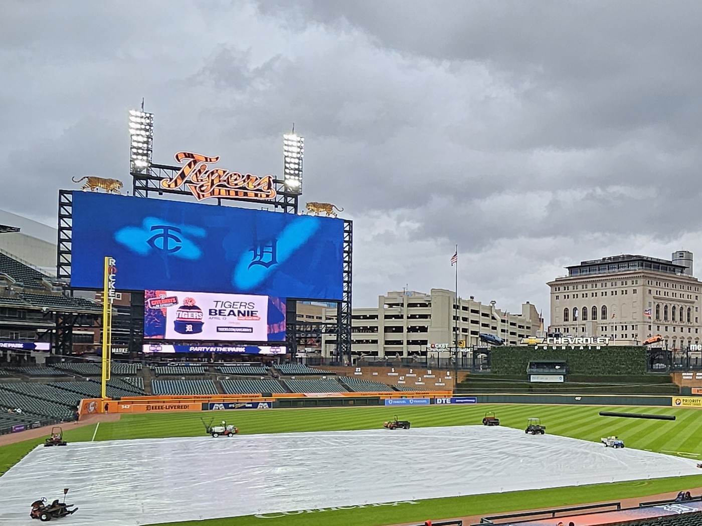 Script 'Tigers' sign above the outfield scoreboard at Comerica Park with the field under a rain tarp, April 2024