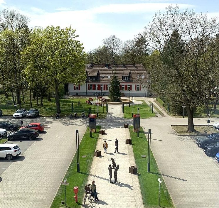 An aerial view of the plaza and walkway in front of the Alte Försterei entrance, with the old forester's house visible among the trees