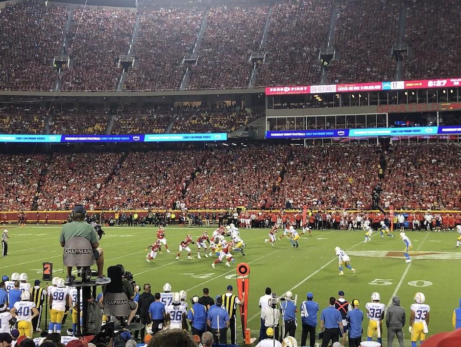 Arrowhead Stadium full of fans in red on a Thursday night, with Chiefs and Chargers players on the field
