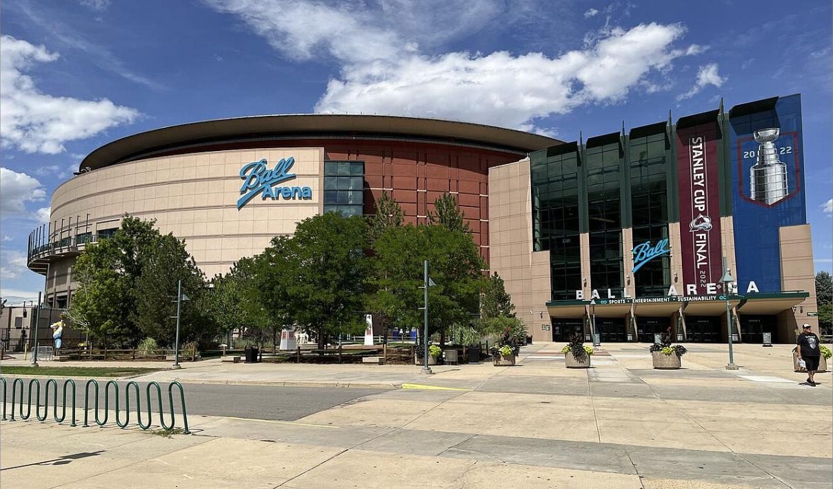 Ball Arena's exterior under a blue sky with a 2022 Stanley Cup Final banner hanging at the entrance