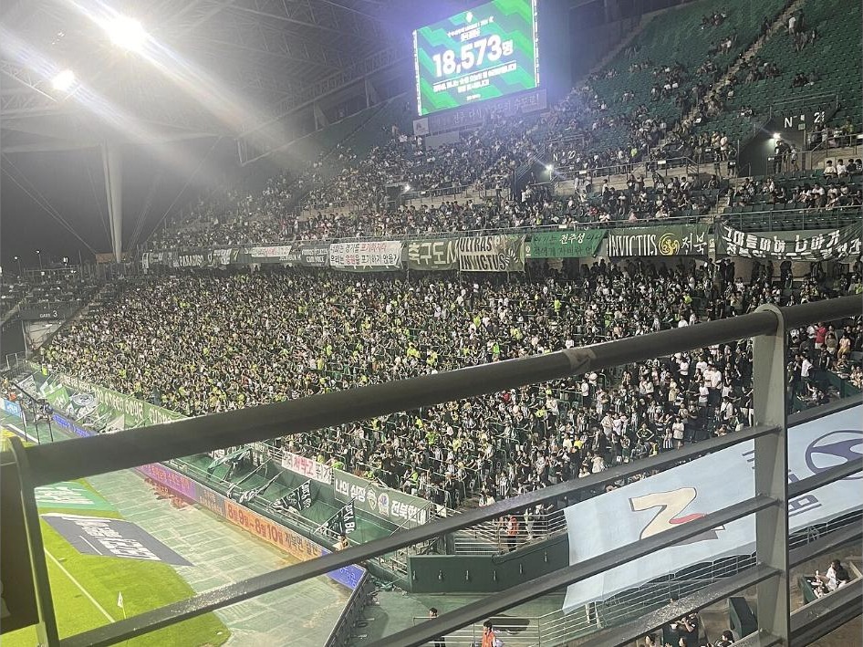 Jeonbuk fans filling the stands under the scoreboard during a night game