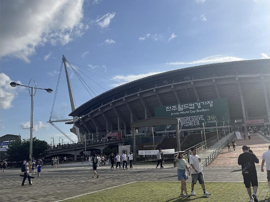 Exterior of Jeonju World Cup Stadium under a blue sky as fans arrive